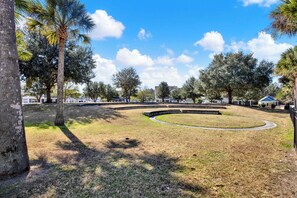 Un parque con un sendero circular, árboles y cielo despejado.