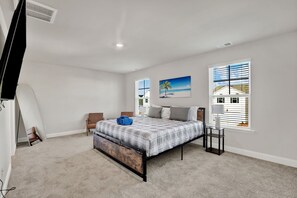Un dormitorio con cama, un cuadro, una ventana y una lámpara.
