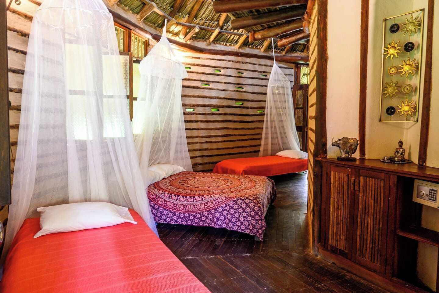 A room with two beds, each with a canopy, and a small table with decorative items.
