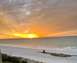 Ein Strand bei Sonnenuntergang, mit Meer und einigen Spaziergängern.
