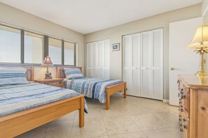 Une chambre à coucher avec deux lits, une table de chevet, une lampe, une commode et un placard avec des portes à persiennes.