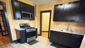 A kitchen with dark cabinets, a microwave, an oven, and a sink.