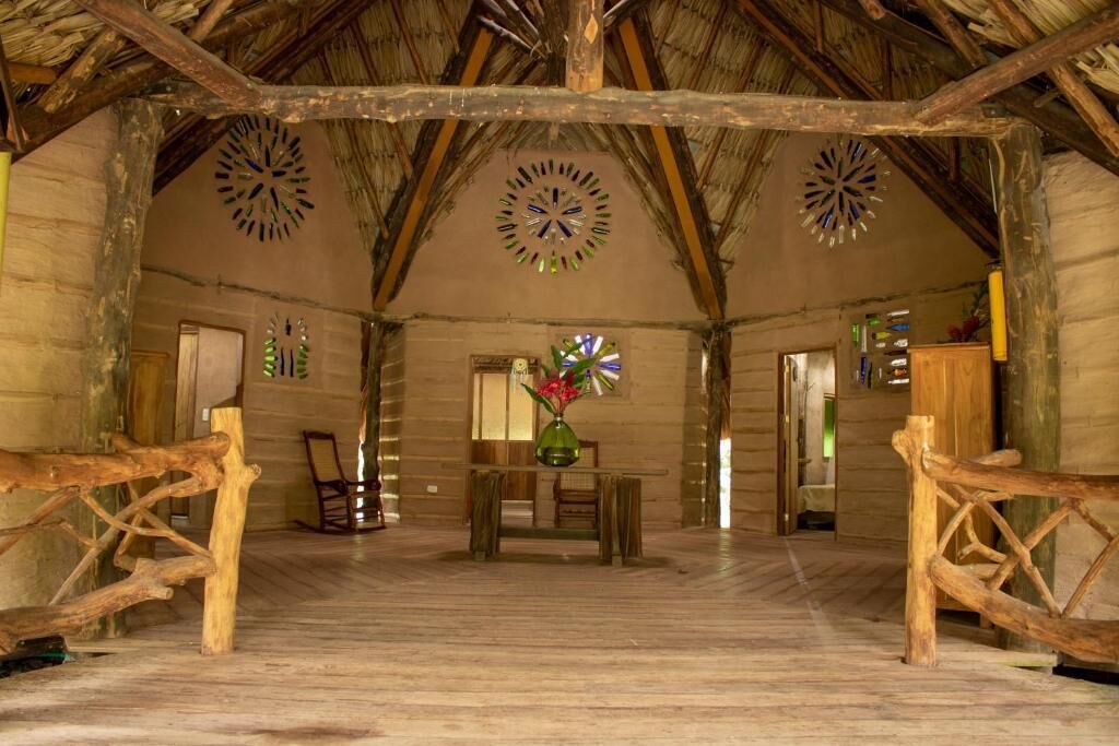 A rustic interior with wooden beams, a central table with chairs, and decorative wall art.