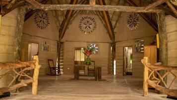 A rustic interior with wooden beams, a central table with chairs, and decorative wall art.