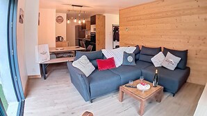Una sala de estar moderna con un sofá modular, un revestimiento de pared de madera y un comedor al fondo.