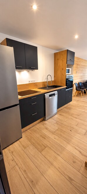 Eine moderne Küche mit Geschirrspüler, Mikrowelle und einem Holzkasten.