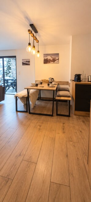 Eine moderne Küche mit einem Holztisch, Stühlen und einer Pendelleuchte.