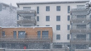 Um edifício com várias janelas e uma área coberta na frente.