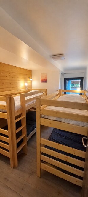 Una habitación con literas, una lámpara de pared y una ventana con vistas.