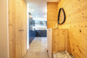 A wooden interior hallway leading to a kitchen with modern appliances and a visible ceiling light. - travelski home premium - Résidence La Mariande - 3 Pièces 6 personnes N°0.3 (Les Deux Alpes)