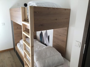 Ein Stockbett mit Holzrahmen und weißer Bettwäsche.