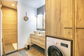 Casa de banho compacta com toucador de madeira, máquina de lavar e suporte para toalhas.