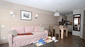 Ein modernes Wohnzimmer mit einer Couch, einem Essbereich mit Stühlen, einer Küche mit einer Mikrowelle und einem großen Spiegel.