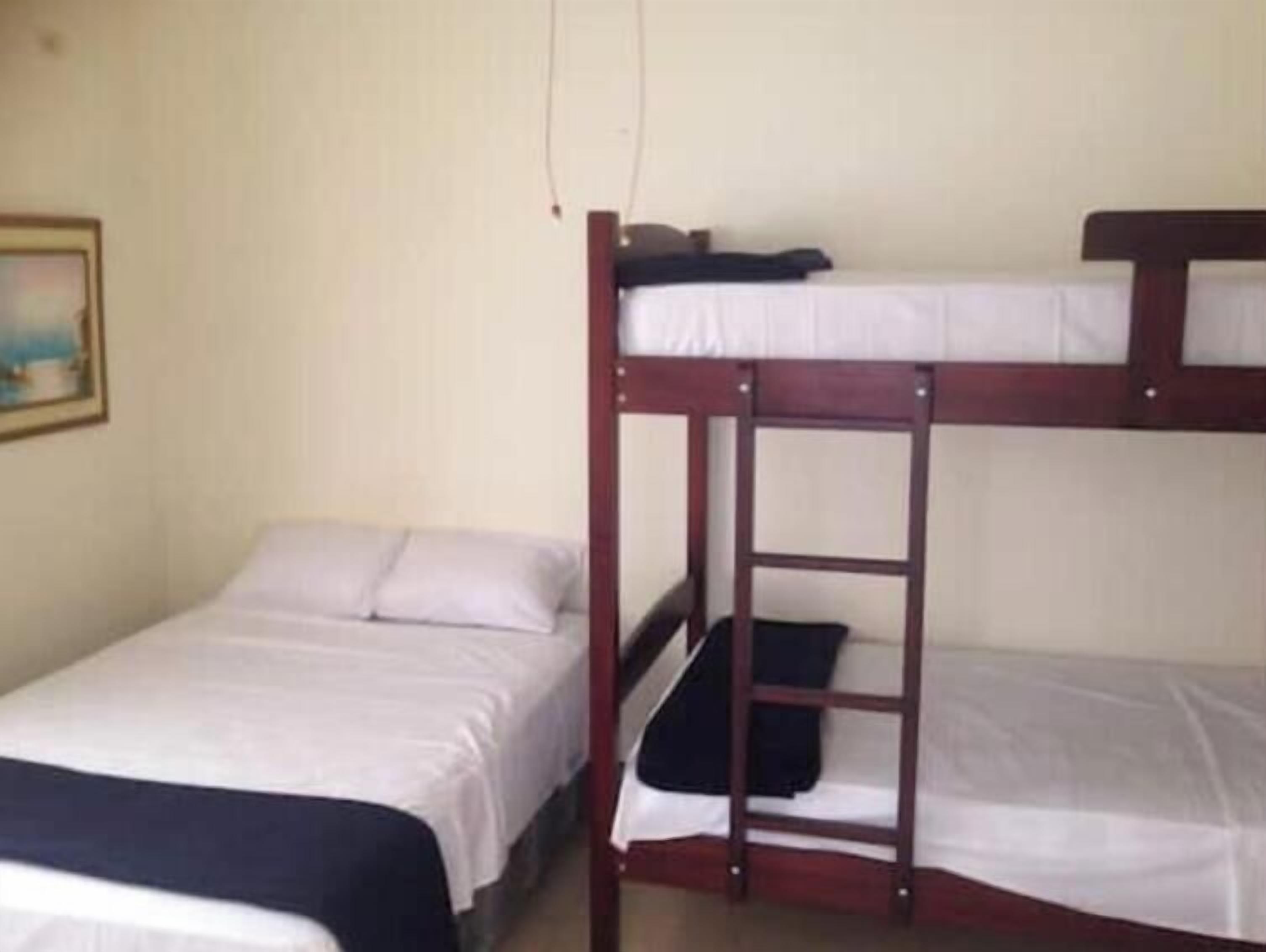 Uma beliche com escada, uma cama de solteiro e um quadro pendurado na parede.