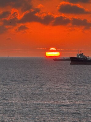 Un atardecer sobre el océano con un barco en primer plano.