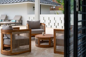 A patio area with wicker furniture, including a sofa, armchairs, and a round table. - 5BR Luxe Retreat in Runaway Bay ~ Private Pool ~ Beach Access (Runaway Bay)