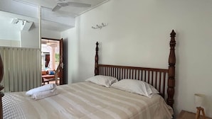 A bedroom with a bed, a nightstand, a lamp, a ceiling fan, and a wall-mounted light fixture.