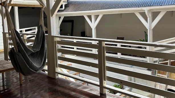A hammock suspended from a ceiling in a room with a wooden floor and white railings.