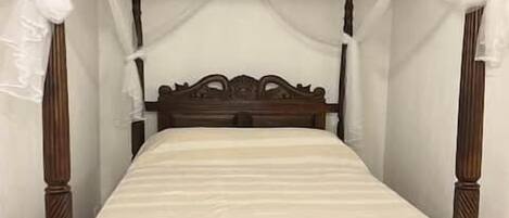 A four-poster canopy bed with a wooden frame and white bedding.