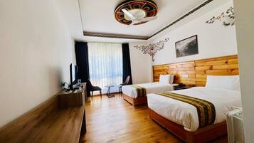 Quarto de hotel com duas camas, cabeceira de madeira, escrivaninha com cadeira, mesinha e janela com cortinas.