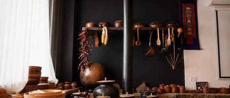 A traditional kitchen with a sign reading 'BHUTAN KITCHEN,' featuring wooden utensils, pots, and a large pot on a table.