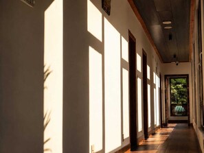 A corridor with a series of doors and windows allowing natural light to enter. - Hotel River Valley Paro (Paro)