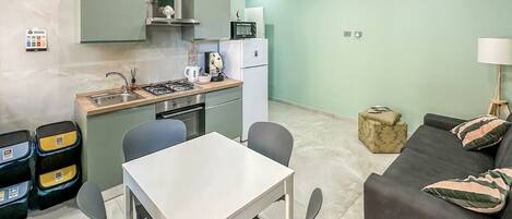 Un espacio habitable compacto con kitchenette, comedor y zona de estar.