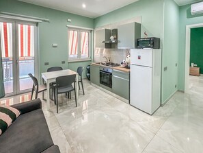 A compact kitchen with a dining area, a sofa, and a view through the window. - Karim's House - Portici (Portici)