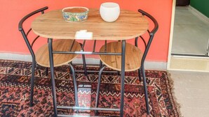 A round wooden table with metal legs, two chairs, a patterned bowl, and a white cup on the table. - Karim's House - Portici (Portici)