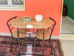 A round wooden table with metal legs, two chairs, a patterned bowl, and a white cup on the table. - Karim's House - Portici (Portici)