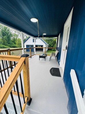 A covered outdoor area with a wooden railing, a bench, and a grill. - Cottage by Niagara River (Fort Erie)