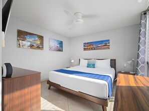 A hotel room with a bed, a desk, and a ceiling fan. - Kihei, Kamaole Nalu, Spacious 4 BR, Beachfront, Sleeps 12 (Kihei)