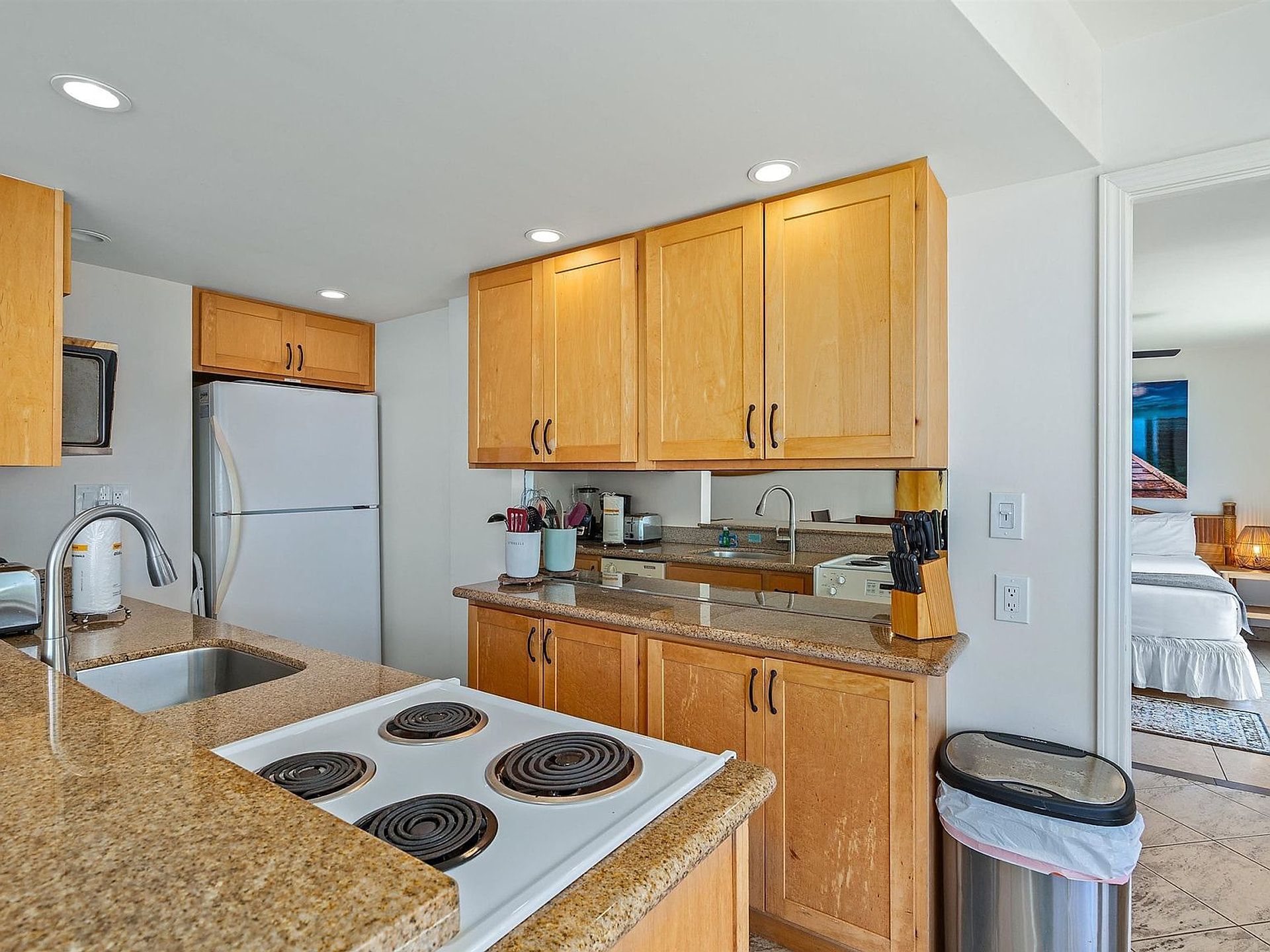 A compact kitchen with wooden cabinets, a white stove, and granite countertops.