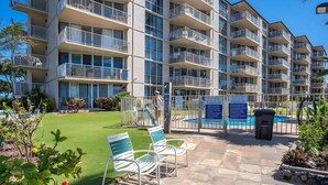 A multi-story residential building with balconies, a swimming pool, and outdoor seating. - Beachfront 4BR, 2 Condos for 12 in Kihei! (Kihei)