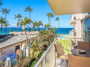 A balcony with a view of the ocean, palm trees, and a pool area. - Kihei, Kamaole Nalu, Spacious 4 BR, Beachfront, Sleeps 12 (Kihei)