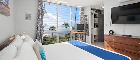 Habitación de hotel con una cama, un escritorio, un televisor y vistas al exterior.