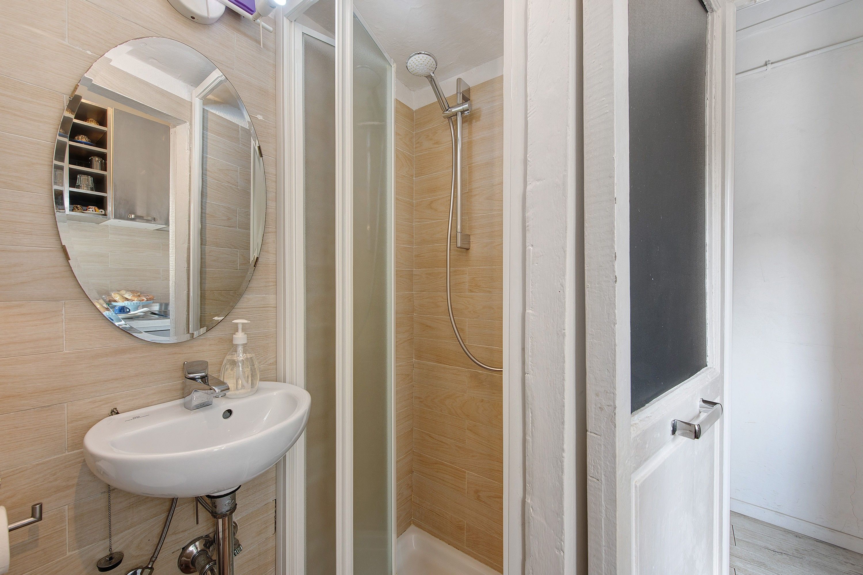 A bathroom with a white sink, a mirror, and a shower area.