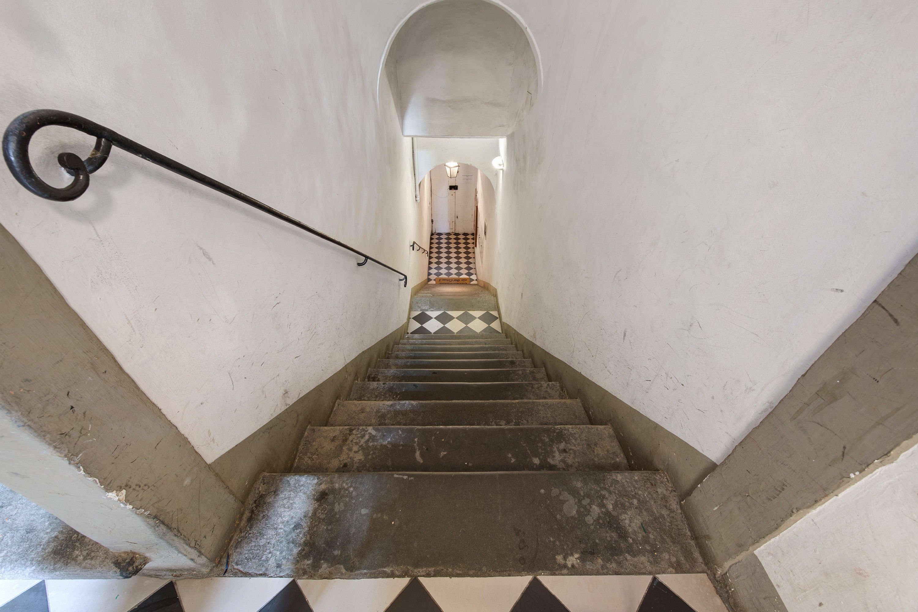 A staircase with a metal handrail leading to a door at the top.