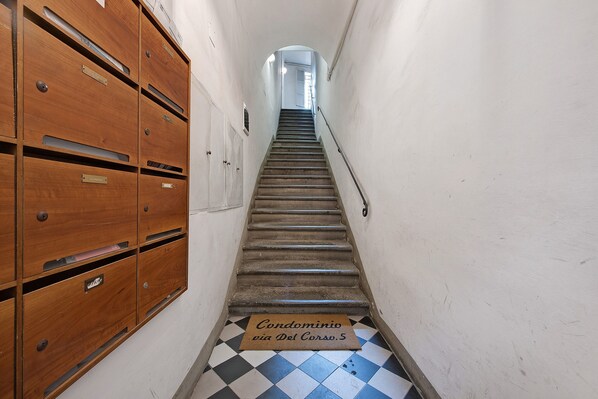 Un pasillo estrecho con un armario de madera a la izquierda y una escalera que sube a una plataforma.