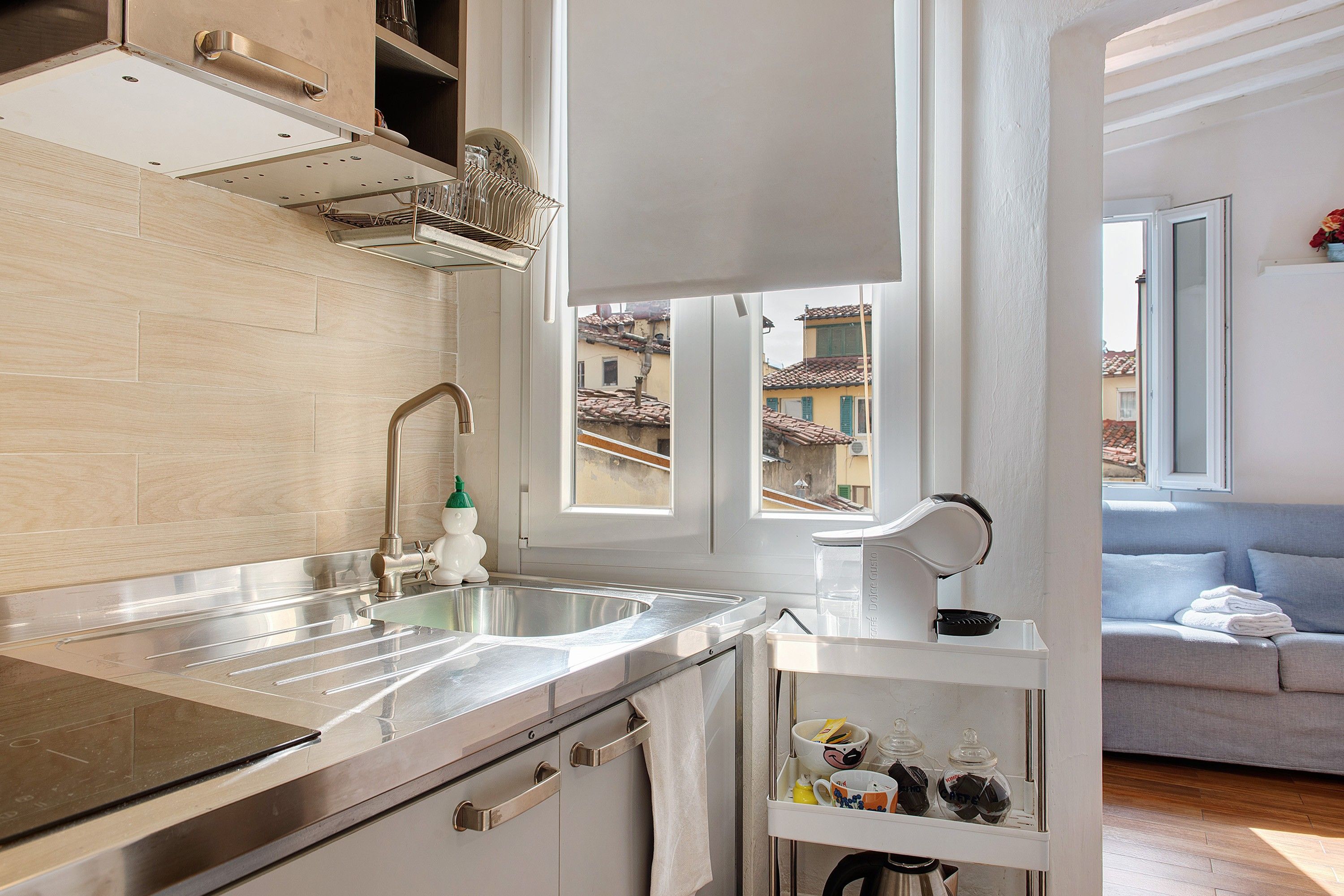 A modern kitchen with a stainless steel sink, a built-in oven, and a window overlooking a cityscape.