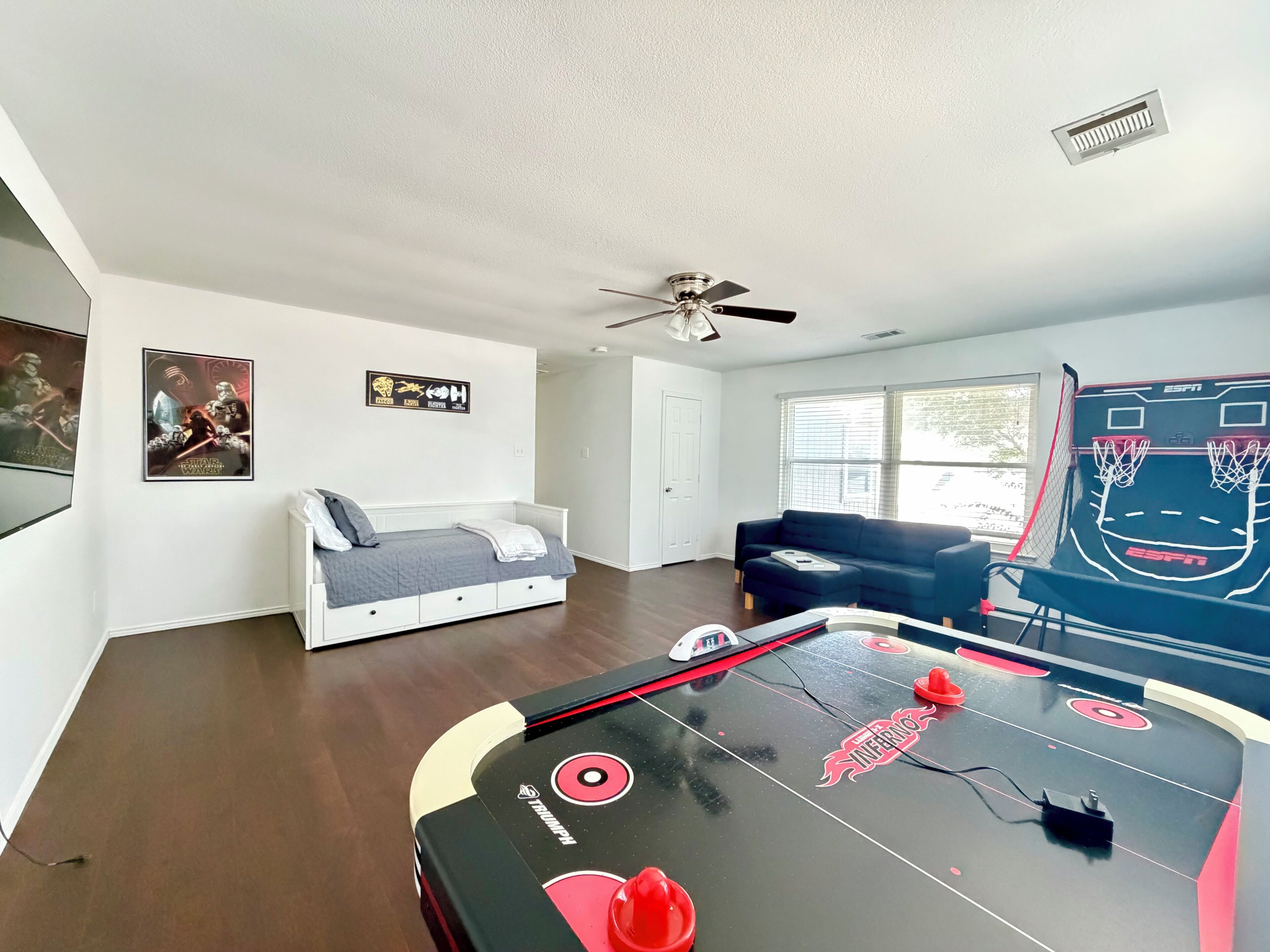 A room with a pool table, a bed, a couch, and a ceiling fan.