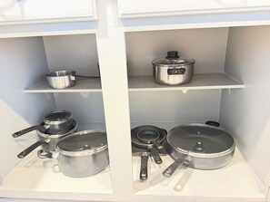 Una cocina con utensilios de cocina y ollas de acero inoxidable en estantes.