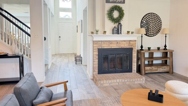 A living room with a fireplace, a staircase, and a view of the outside. - Luxe Family Retreat -Sleeps 10 - Large Home - Game Room -Private Back Yard (McKinney)