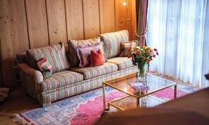 A cozy living room with a patterned sofa, a glass coffee table, and a floral vase. - AN EXCEPTIONAL COMBINATION OF SPACE, COMFORT & ALPINE ELEGANCE ,MATTERHORN VIEWS (Zermatt)