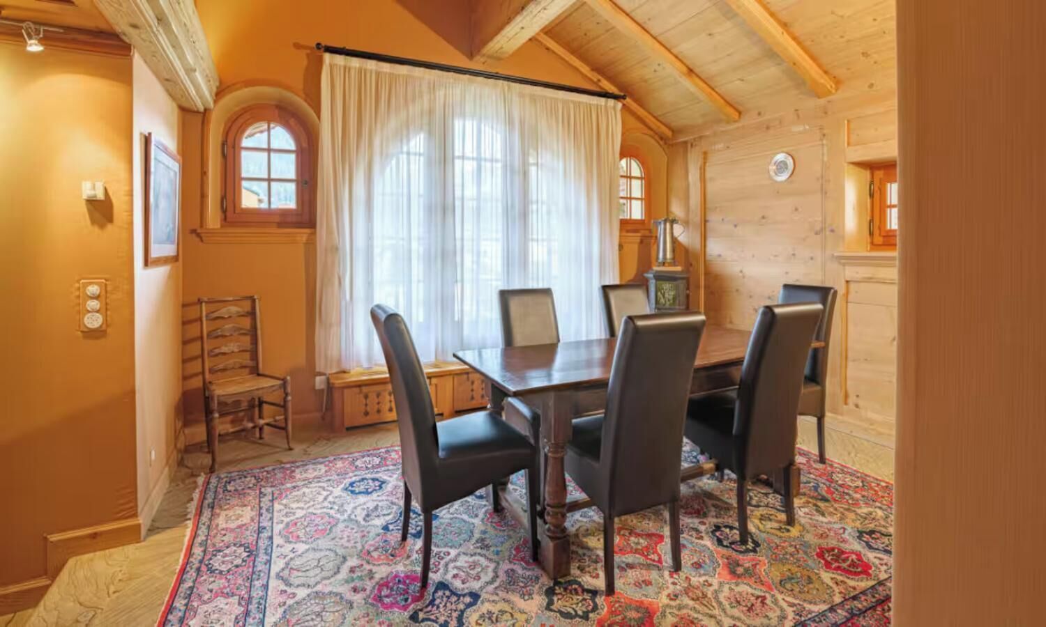 Ein Essbereich mit einem Holztisch, vier Stühlen und einem gemusterten Teppich.