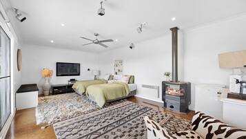 A modern bedroom with a bed, a television, a fireplace, and a ceiling fan.