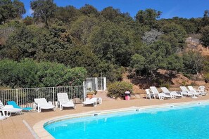 A swimming pool with lounge chairs and a fenced area, surrounded by trees and a hilly landscape. - Casa di Toro:House in front of the sea at Palombaggia, 2/8 p (Porto-Vecchio)