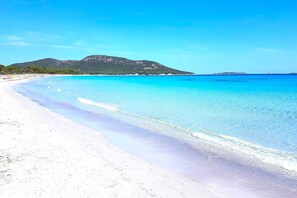 Une plage à l’eau turquoise et limpide et au sable blanc.