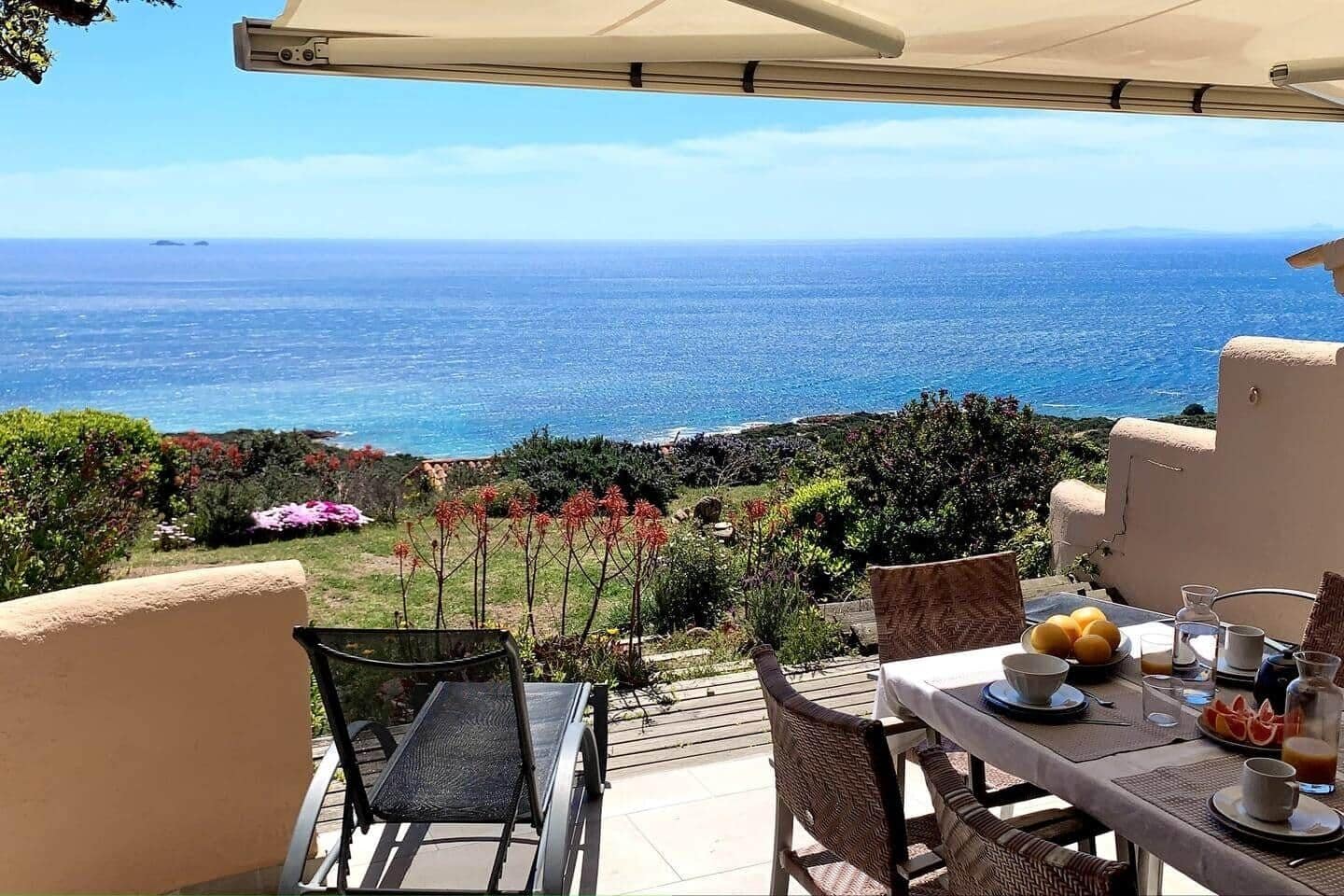 Een terras met een ontbijttafel met uitzicht op de kust.