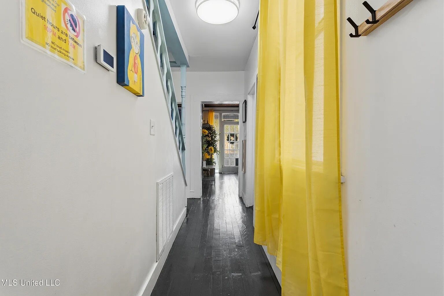 A hallway with a yellow curtain, a sign indicating quiet hours, and a door leading to a room with a view.